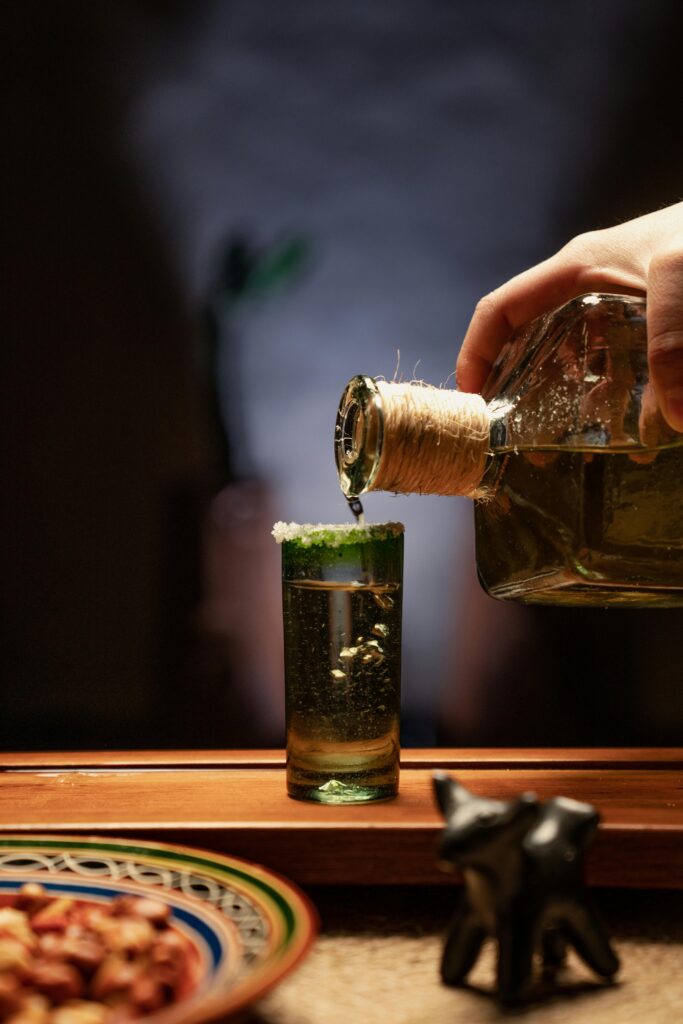 pexels-photo-7603331-7603331 Hand pouring tequila into a salt-rimmed shot glass, capturing a traditional Mexican drink moment.